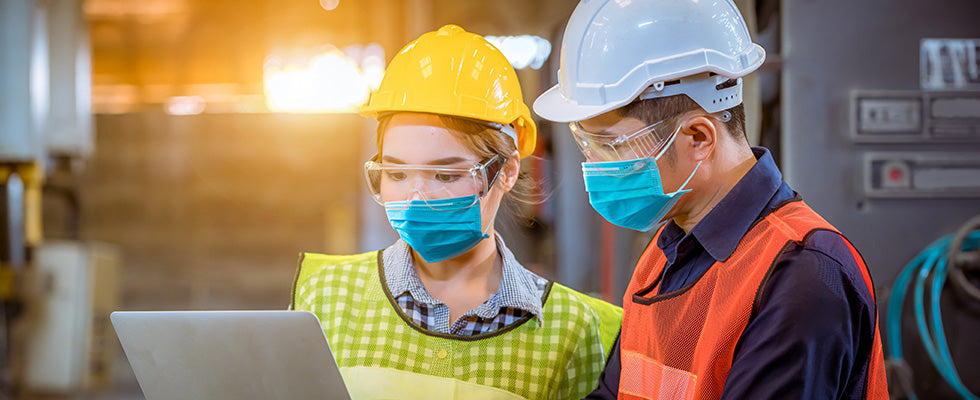 Woman and man wearing face masks and safety vests